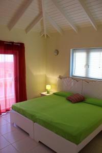 una camera da letto con un letto grande con una coperta verde di CAS IGUANA - Curacao - Villapark Fontein - Ferienhaus mit Pool a Fontein