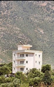 a large white building in front of a mountain at Vila Bakalli in Vlorë