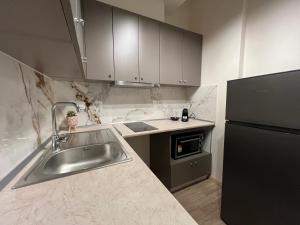 a kitchen with a sink and a black refrigerator at Oasis Apartment 2 by GG in Alexandroupoli