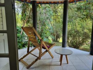 a wooden rocking chair on a porch with a table at Casa na Serra para 14 Pessoas com Piscina e Churrasqueira - Da Francesa in Bom Jardim