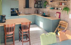a kitchen with blue cabinets and a counter and chairs at Beautiful Home In Risør With Kitchen in Risør