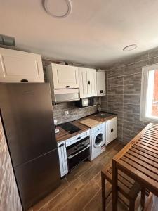 a kitchen with white cabinets and a black refrigerator at Apartamento calera in Burgos