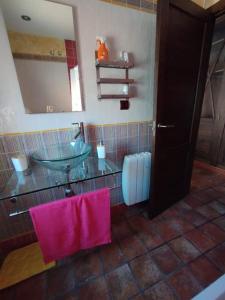 a bathroom with a sink and a mirror and pink towels at Casa La Peguera in La Parra