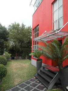 a red building with a palm tree and an umbrella at Red Square Home in Pretoria