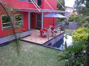 een rood huis met een terras met een tafel en een paraplu bij Red Square Home in Pretoria