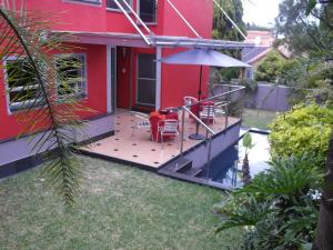 a red house with a deck with a table and an umbrella at Red Square Home in Pretoria