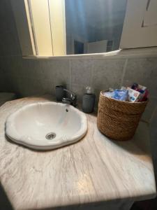 a bathroom sink with a basket of toiletries on a counter at Christina's Apartment in Stratónion +16 photos