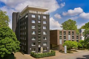 ein hohes schwarzes Gebäude neben einigen Gebäuden in der Unterkunft the Deutz, a Tribute Portfolio Hotel in Köln