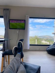 a person laying on a chair watching a soccer game at Casa Carlos Paz, 6 personas in Estancia Vieja