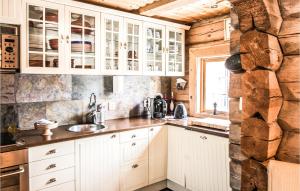 eine Küche mit weißen Schränken und einer Steinmauer in der Unterkunft Stunning Home In Østby With Kitchen in Østby