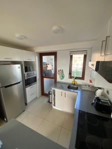 a kitchen with a stainless steel refrigerator and white cabinets at Departamento Puerto Velero in Tongoy