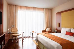 a hotel room with a bed and a desk and a window at Courtyard by Marriott Kochi Airport in Nedumbassery