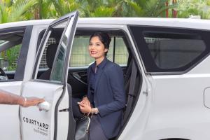 a woman is getting out of a van at Courtyard by Marriott Kochi Airport in Nedumbassery