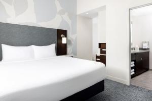 a hotel room with a white bed and a mirror at Residence Inn by Marriott New York Downtown Manhattan/World Trade Center Area in New York