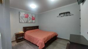 a bedroom with a bed with a red bedspread at Hotel Posada San Laureano in Tunja