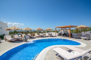 
a beach with a pool, chairs, and a pool table at Orama Apartments in Agia Anna Naxos
