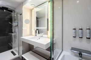 a white bathroom with a sink and a shower at AC Hotel Paris Porte Maillot by Marriott in Paris