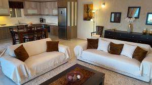 a living room with two white couches and a kitchen at Villa Christina Luxury in Vouliagmeni Lake