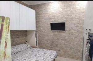 a bedroom with a bed and a tv on a brick wall at Casa Maria in Montallegro