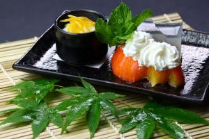 a black plate of food with fruit and whipped cream at Baigetsu Ryokan in Shimo-suwa