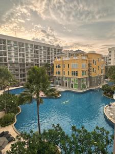 a large swimming pool with a palm tree in front of buildings at Arcadia beach 网红水系公寓一房 Nice view 专业的健身房 桑拿 中心位置 交通便利 Smart tv WiFi in Pattaya South