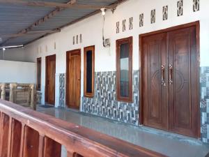 a row of wooden doors in a room with a railing at Hendi Homestay in Gili Gede