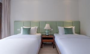 two beds sitting next to each other in a room at Mount Emei Heyuan Serene Residence Hot Spring Hotel in Emeishan City