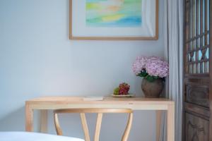 a table with a vase of flowers and a vase of fruit at Mount Emei Heyuan Serene Residence Hot Spring Hotel in Emeishan City