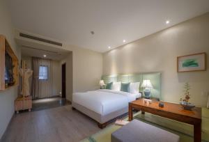 a bedroom with a large white bed and a table at Mount Emei Heyuan Serene Residence Hot Spring Hotel in Emeishan City