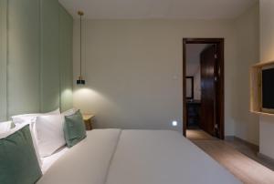 a bedroom with a large white bed with green pillows at Mount Emei Heyuan Serene Residence Hot Spring Hotel in Emeishan City