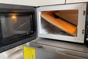 a microwave is open with a piece of cardboard inside at Hermoso y Cómodo Departamento in Ciudad del Carmen