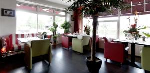 a restaurant with tables and chairs and a palm tree at Hotel Cuba Libre in Vijlen