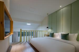 a bedroom with a large white bed with green walls at Mount Emei Heyuan Serene Residence Hot Spring Hotel in Emeishan City