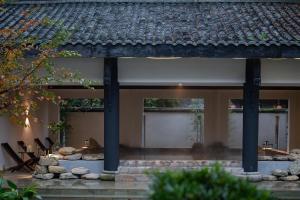 an external view of a house with columns and rocks at Mount Emei Heyuan Serene Residence Hot Spring Hotel in Emeishan City
