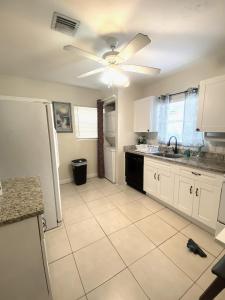 Il comprend une cuisine avec des placards blancs et un ventilateur de plafond. dans l'établissement Casa Historica, a cozy 1940 cottage in Delray Beach, FL, à Delray Beach