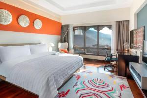 a bedroom with a bed and a desk and a window at Le Meridien Thimphu in Thimphu