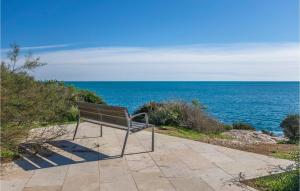 a bench sitting on a sidewalk looking at the ocean at Cozy Home In Hospitalet De Linfant in Hospitalet de l'Infant