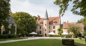 a large building with a spire in a park at Château - Hôtel Le Sallay in Magny-Cours