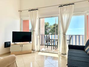 a living room with a couch and a television and a balcony at Apartment Elaine's View in Umag