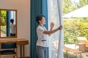 a woman is looking out of a window at Chiều Hạ Village - Spirit of Riverside in Hoi An