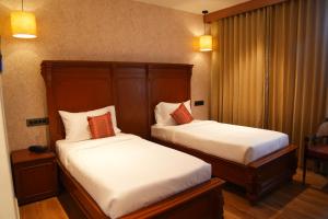 two beds in a hotel room with white and red pillows at Capital Luxury Suites in Vijayawāda