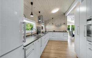 a kitchen with white cabinets and a wooden floor at Holiday Home Oksbøl - 06 in Oksbøl