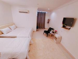 a hotel room with two beds and a tv at The Blossom Hotel in Simpang Empat