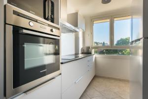 eine Küche mit weißen Schränken und einem großen Backofen in der Unterkunft Charmant Appartement Familial in Martigues