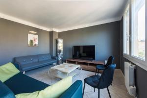 ein Wohnzimmer mit einem blauen Sofa und einem Fernseher in der Unterkunft Charmant Appartement Familial in Martigues + 9 Fotos