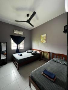 a bedroom with two beds and a ceiling fan at Taiping Homestay Husna Afina in Taiping