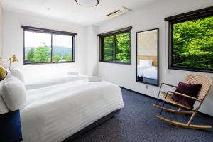 a bedroom with a bed and a chair and windows at Happo Apartments by HHG in Hakuba