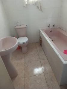 a bathroom with a toilet and a tub and a sink at The Quaint Cottage in Livingstone +4 photos