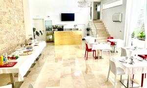 a restaurant with white tables and chairs and a staircase at AuGuStea in Sannicandro di Bari