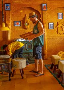 un uomo che tiene una scatola in soggiorno di Open Road Hostel and Cafe a Jaisalmer